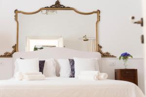1 cama blanca con almohadas blancas y espejo en Relais Carlo Alberto en Salve