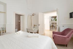Dormitorio blanco con cama blanca y silla rosa en Relais Carlo Alberto en Salve