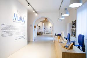 un couloir avec une grande table et des chaises bleues dans l'établissement MuMA Hostel, à SantʼAntìoco