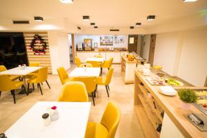 a dining room with tables and yellow chairs at KViHotel Budapest - the smart hotel in Budapest