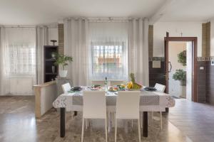 a dining room with a table and white chairs at Appartamento Greco by BarbarHouse in Borgagne