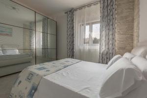 a bedroom with a white bed and a window at Appartamento Greco by BarbarHouse in Borgagne