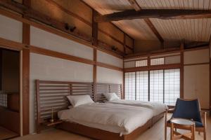 um quarto com uma cama grande e uma cadeira azul em TANIYA em Takayama