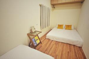 a small room with two beds and a wooden floor at 寮寓Laos House in Xiaoliuqiu