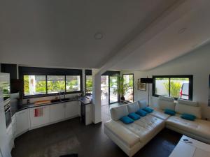 Villa Pluton - Meublé de tourisme 4 étoiles في سان جيل لي بان: غرفة معيشة مع أريكة بيضاء ووسائد زرقاء