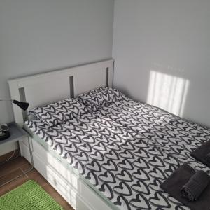 1 dormitorio con 1 cama con edredón blanco y negro en GOX Apartman, en Subotica