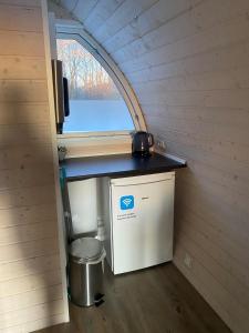 a small refrigerator in a tiny house with a window at Naturhytter in Kjellerup