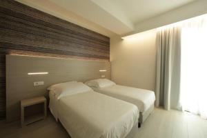 a hotel room with two beds and a window at Hotel San Marco in Peschiera del Garda