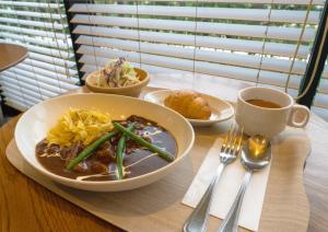 Ours Inn Hankyu في طوكيو: طاولة مع وعاء من الطعام وكوب من القهوة