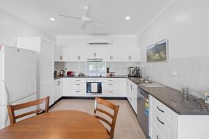 a kitchen with white cabinets and a table and chairs at Cardwell Seascape Apartments in Cardwell
