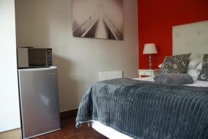 1 dormitorio con 1 cama y TV en Flutterby Guesthouse en Potchefstroom