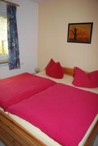 - une chambre avec 2 oreillers rouges sur un lit dans l'établissement Ferienhäuser Heideröslein, à Fürstenberg-Havel