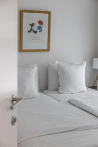 a white bed with white pillows and a picture on the wall at Milano Ostend - Casselbergh Residences in Ostend +16 photos