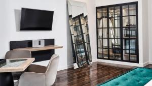 uma sala de estar com uma televisão e uma mesa e cadeiras em Katikies Garden Santorini - The Leading Hotels Of The World em Fira