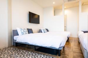 2 camas en una habitación con TV en la pared en BAYSIDE KANAYA, en Futtsu