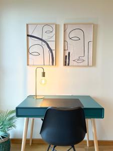 einen blauen Schreibtisch mit einem Stuhl und zwei Gemälden in der Unterkunft Apartamento de diseño con Gym y Piscina in Castellón de la Plana