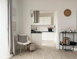 a white kitchen with a chair and a clock on the wall at An cosy apartment near CPH airport in Copenhagen