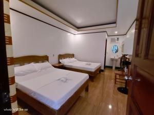 two beds in a small room with a door at Rabang Traveller's Inn in San Vicente