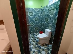a bathroom with a toilet and a tile wall at Rabang Traveller's Inn in San Vicente