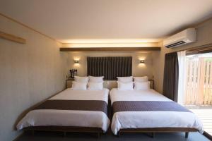 2 łóżka w pokoju hotelowym z oknem w obiekcie Jikukan Enishi w mieście Taisha