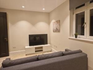a living room with a couch and a flat screen tv at Spacious 2 BR with Balcony in Hendon in Colindale
