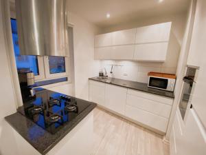 a kitchen with white cabinets and a black counter top at An cosy apartment near CPH airport in Copenhagen