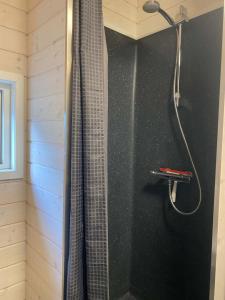 a shower with a shower curtain in a bathroom at Naturhytter in Kjellerup