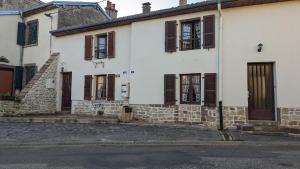 una casa blanca con persianas marrones en una calle en Gîte de la Harpe au 4, en Vauvillers