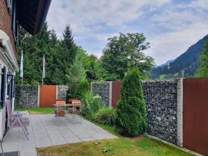 a backyard with a stone fence and a table and chairs at FeWo Stegenbach Oberstaufen/Steibis in Oberstaufen