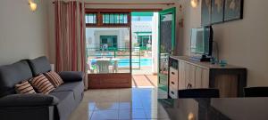 a living room with a couch and a tv at Apartamentos Las Palmeras I in Puerto del Carmen