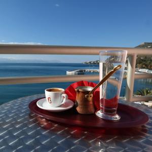 una mesa con un vaso de agua y una taza de café en Hotel Excelsior, en Loutraki