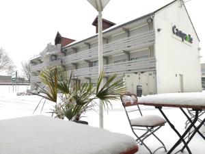 Un edificio cubierto de nieve con dos sillas delante. en Campanile Chambéry, en Chambéry