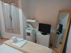 Schlafzimmer mit einem Bett, einem TV und einem Spiegel in der Unterkunft Cau d'en Magí - Apartament Casc Antic in Tarragona