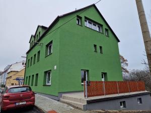 a green building with a red car parked in front of it at Penzion Dubí - Ruská 393 - 110 in Dubí