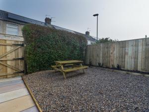 a wooden picnic table in a backyard with a fence at Chestnut House - Cosy 2 bedroom - Ashington in Ashington