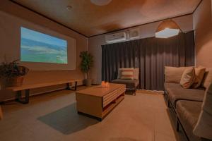a living room with a couch and a large screen at Jikukan Meguri in Kanayama