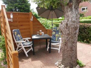 een tafel en stoelen met een parasol naast een boom bij Ferienwohnungen "Kajüte Leer", 15199 in Leer +7 foto's
