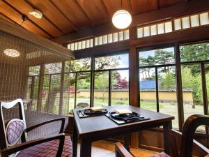 a dining room with a table and chairs and windows at Hakone Suishoen in Hakone