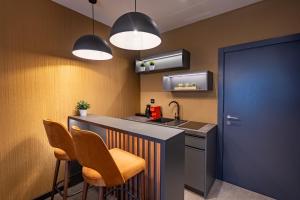 a kitchen with a counter with chairs and a sink at Hotel Element in Novi Sad