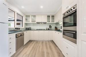 uma cozinha com armários brancos e electrodomésticos de aço inoxidável em Ocean Grove Beach House em Ocean Grove