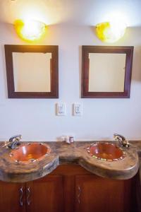 two sinks in a bathroom with two mirrors at Luxe GAME-LODGE bordering Kruger in Phalaborwa