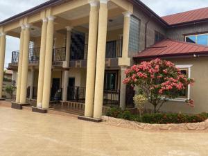 un edificio con columnas y flores en un patio en OKF OBOUBA APARTMENT, en Kumasi
