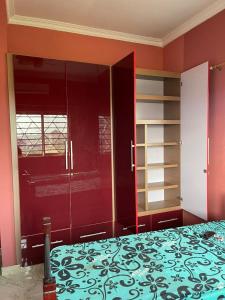a bedroom with red walls and a bed and shelves at OKF OBOUBA APARTMENT in Kumasi