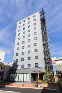 a tall white building on a city street at Sotetsu Grand Fresa Kumamoto in Kumamoto