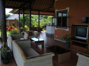 uma sala de estar com cadeiras, uma televisão e uma mesa em Villa Bali Pondok Jepang em Lovina