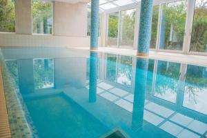 a swimming pool with blue columns in a building at Zsóry Liget Hotel & Spa Superior in Mezőkövesd