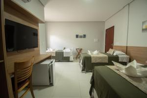 a hotel room with two beds and a flat screen tv at Hotel Araçás in Carolina