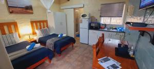 a small room with two beds and a kitchen at Swartberg Cottages in Prince Albert