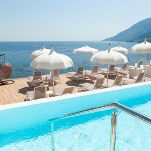 a swimming pool with chairs and umbrellas at Hotel Club Due Torri in Maiori