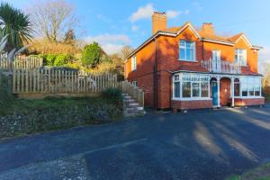 a red brick house with a wooden fence at SAUNTON NORBORO 4 Bedrooms in Braunton
